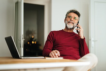 Man in red jumper sat next to a laptop