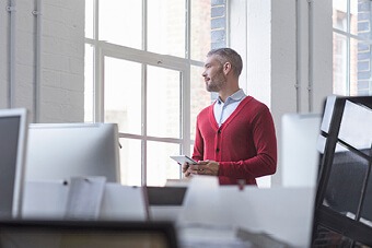 Man in red cardigan looking out of window 