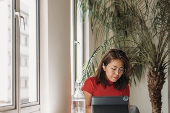 Woman in a red top working on a laptop