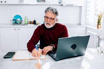 Man writing at desk in kitchen