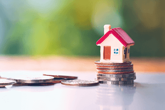 a small house toy on a stack of coins