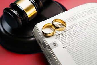 Two wedding rings placed on a book of law open on a page about divorce 