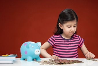 Child with a piggy bank looking at coins