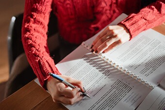 Person in red jumper writing at a desk