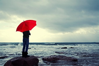 man with red umbrella next to sea