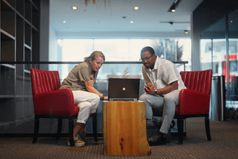 couple sat on an online call on red chairs 