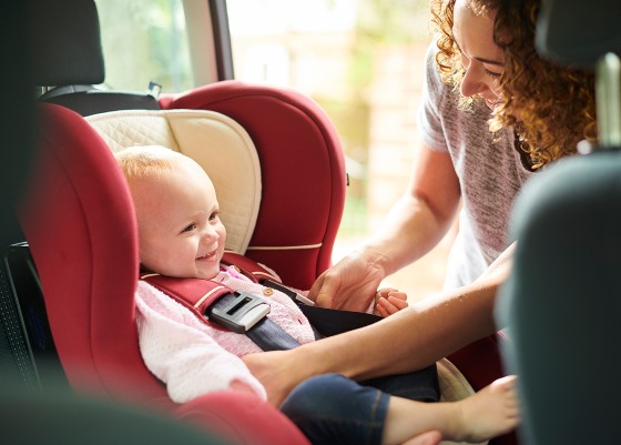 Mother putting baby in car seat