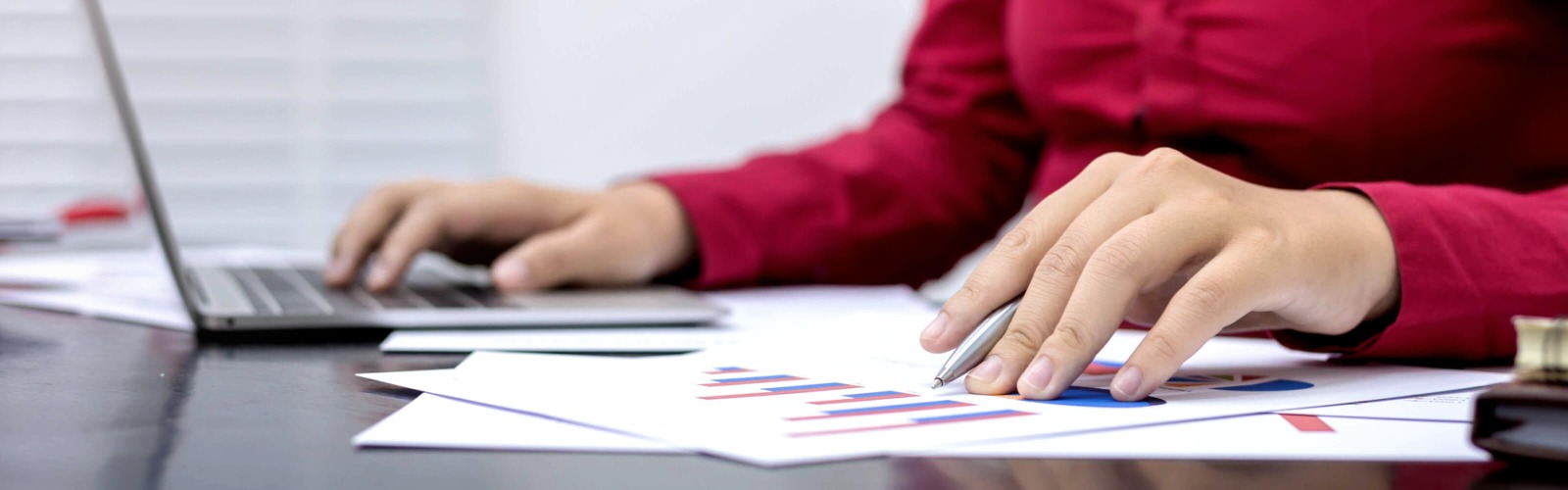 person in red shirt looking at report whilst using calculator 
