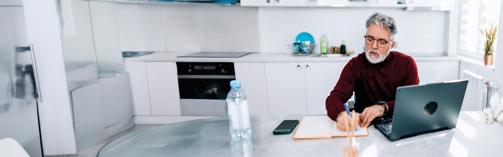 Man writing at desk in kitchen