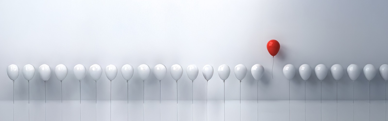 Row of white balloons with a red balloon floating above them