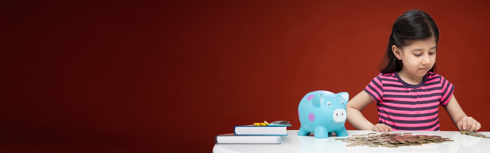Child with a piggy bank looking at coins