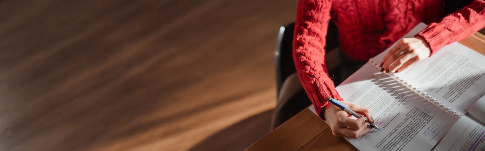 Person in red jumper writing at a desk