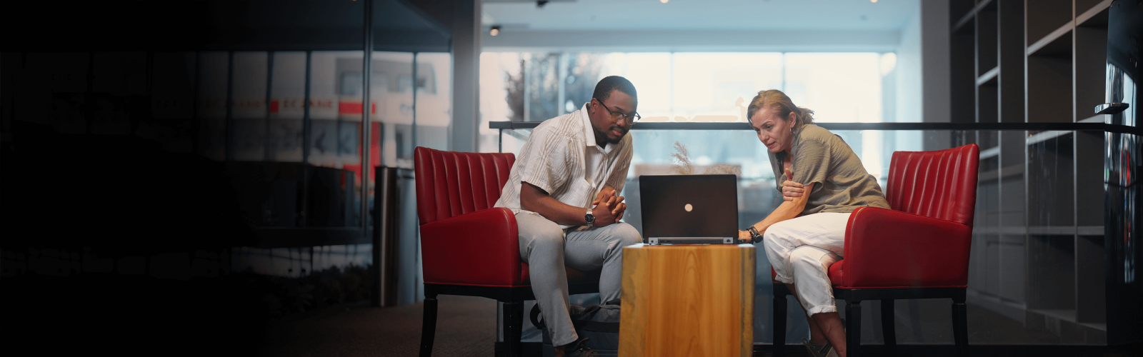 couple sat on an online call on red chairs 