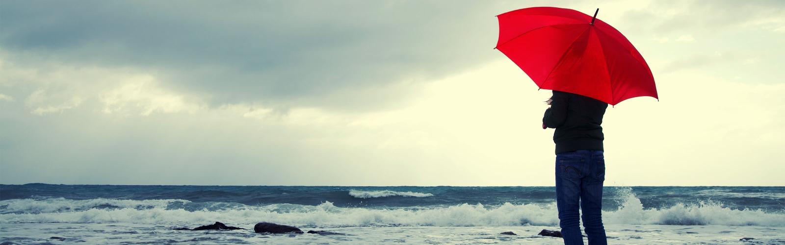 man with red umbrella next to sea