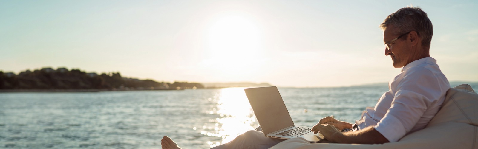 Man relaxing on beach with laptop