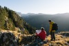 Two men reading a map sat on top of a mountain
