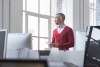 Man in red cardigan looking out of window 
