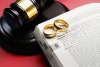 Two wedding rings placed on a book of law open on a page about divorce 