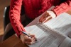 Person in red jumper writing at a desk