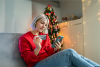 woman holding credit card and phone by Christmas tree